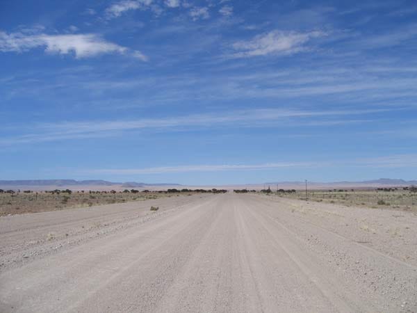 Breite Schotterpiste unter blauem Himmel mit Schleierwolken