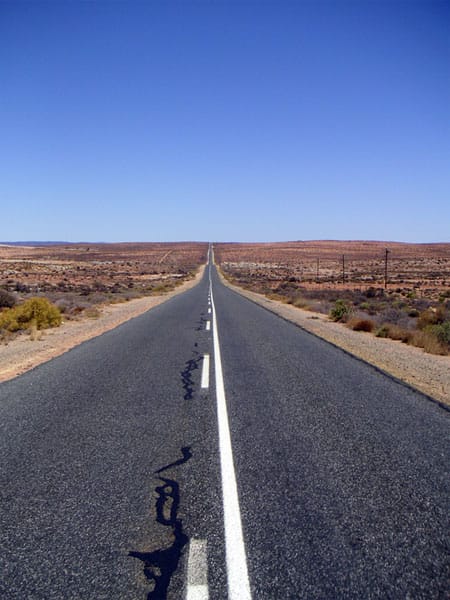 Asphaltstraße, die schnurgerade bis zum Horizont durch trockenes Buschland führt