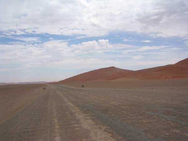 Verwitterte Straße, die auf eine rote Düne zuläuft