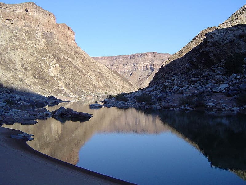 Still water at the bottom of the canyon reflecting the rock walls