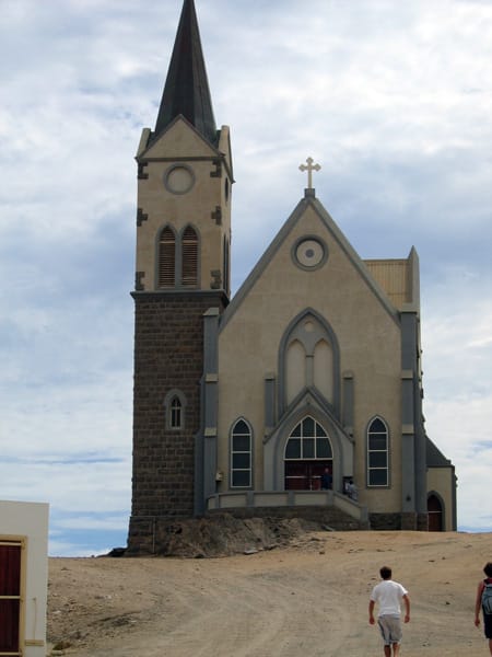Steinkirche mit spitzem Turm auf einer Anhöhe