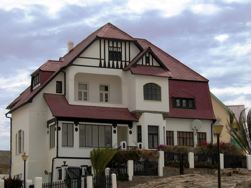 White house with a dark red roof, half-timbered gable and bay window