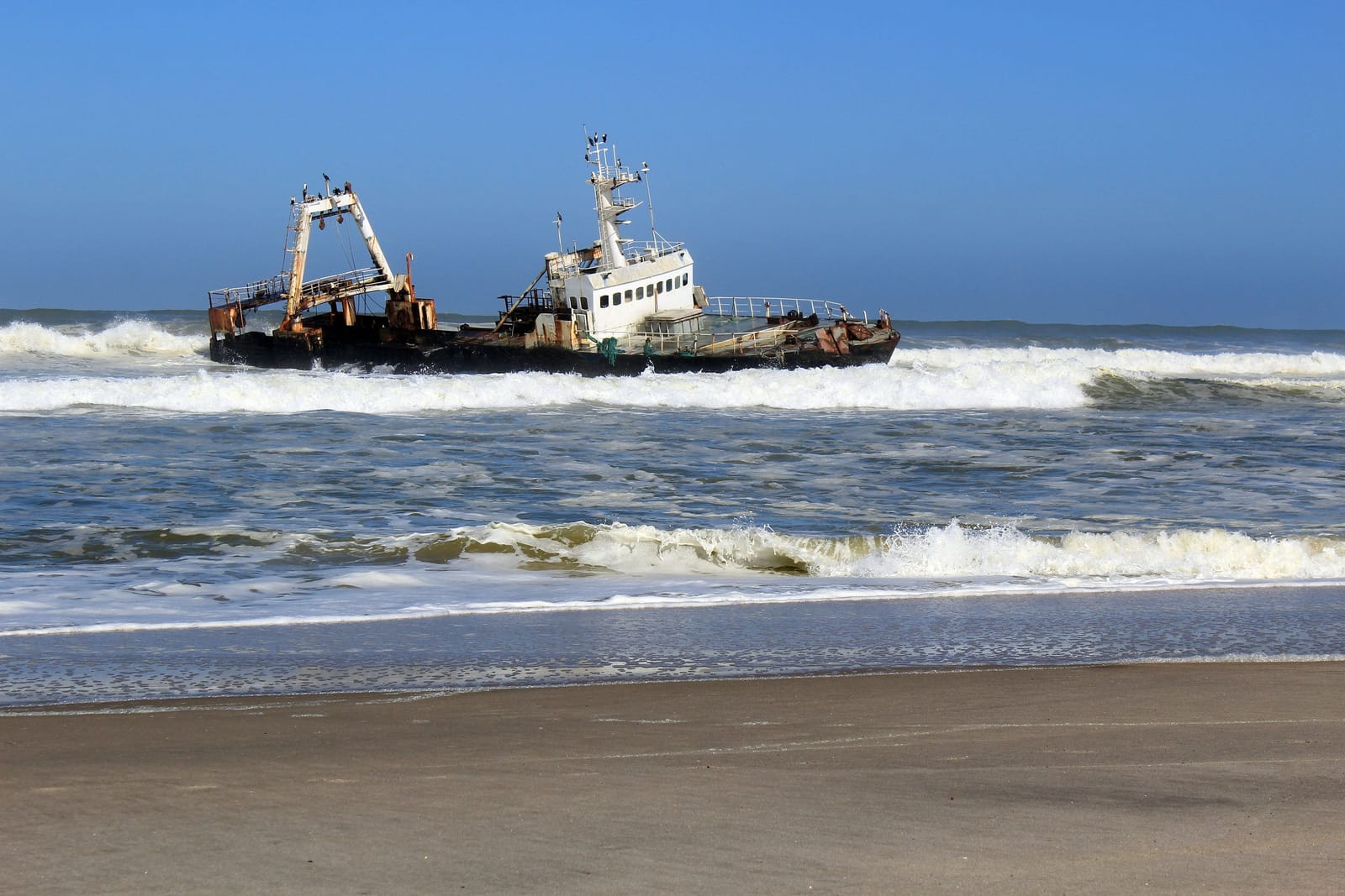 Wrack eines Fischtrawlers in der Brandung vor einem Sandstrand